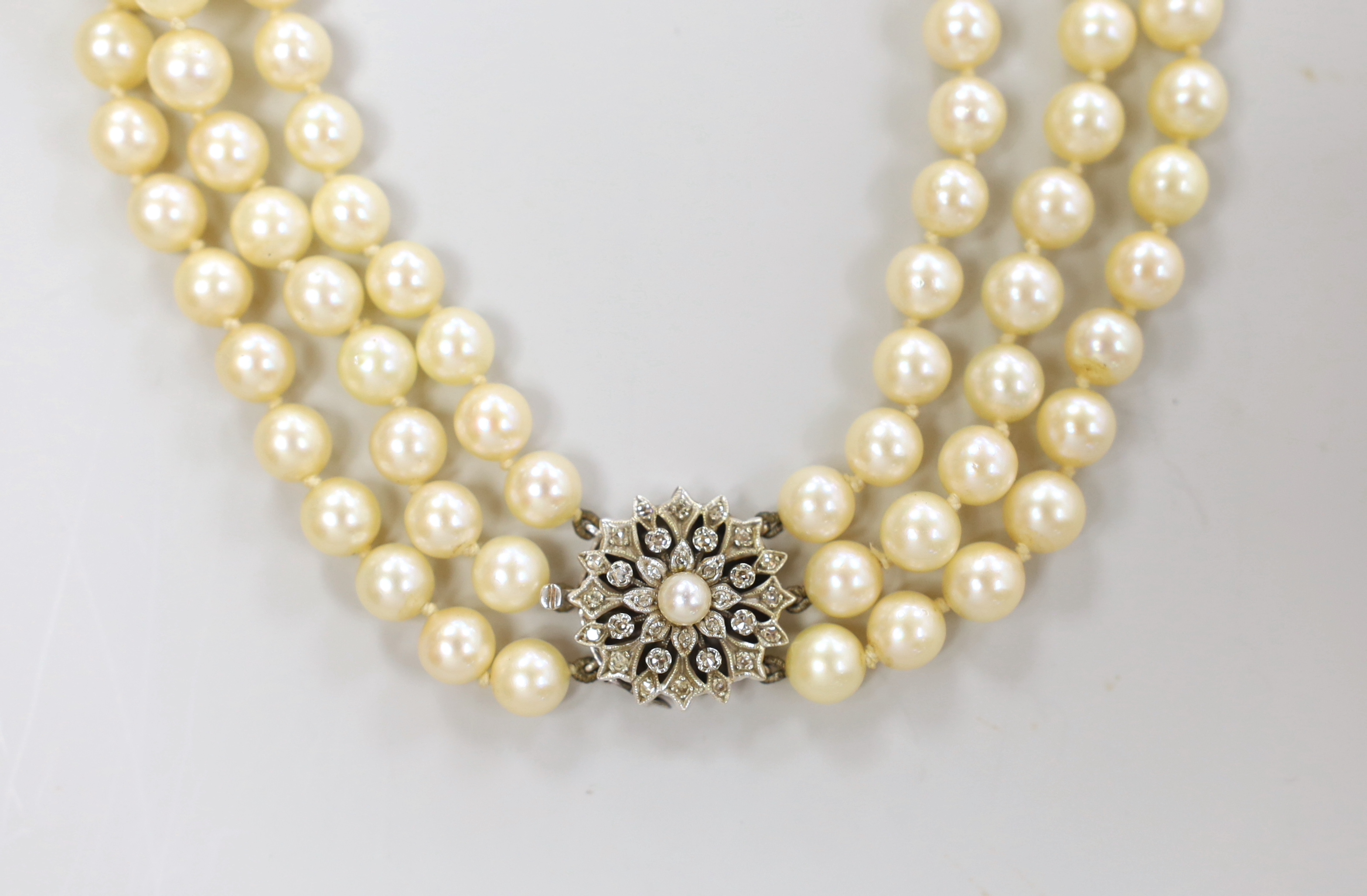 A 1960's triple strand cultured pearl choker necklace, with diamond and cultured pearl cluster set white metal clasp, 40cm, with box and 1968 original purchase receipt.